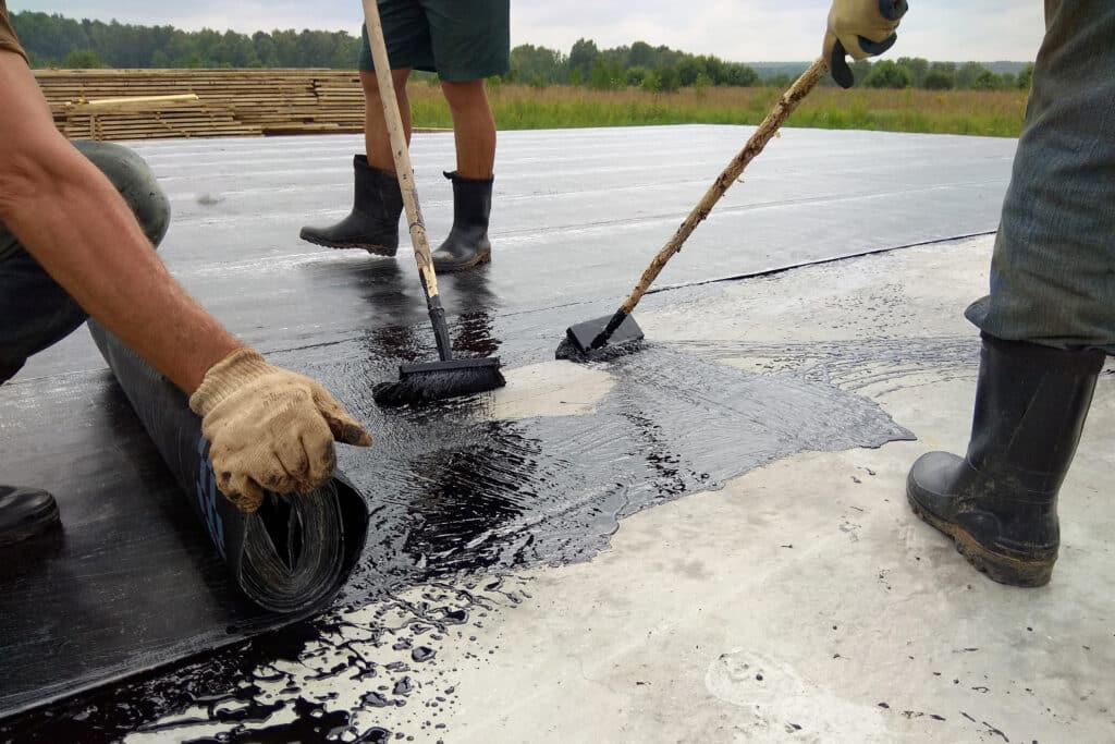 Workers apply modified bitumen to a flat roof